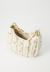 Crochet bag in soft cream with gold accents and decorative clear gems. Zip top closure and detachable gold chain strap. Rounded shape.