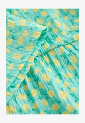 Világoskék szövet sárga citrom és zöld levél mintával, texturált felülettel és ráncolt varrási részletekkel.