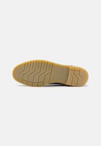 Sole de pantof din cauciuc cu un model de profil hexagonal. Culoare galbenă, textură netedă și o amprenta subtilă a logo-ului aproape de toc.