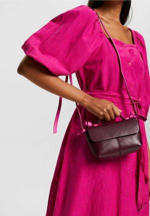 Fuchsia Leinenkleid mit Puffärmel, Knopfleiste und einem Gürtel in der Taille. Dunkelbraune Lederhandtasche mit rosa Rüschendetails.