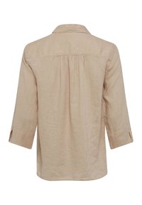 Light tan, long-sleeve shirt with a collar, pleats at the back, and rolled cuffs. Made of a textured fabric with a subtle pattern.