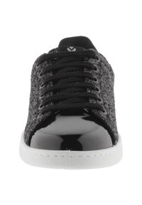 Svart glittrande sneaker med svarta snören, blank svart tåskydd och vit gummisula, framsidesvy.