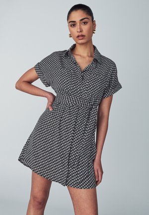 Mustardress mustriga mustriga mustriga, lühikeste varrukatega, kaelusega, vormitud talje ja laienev seelik. Sile kangatekstuur.