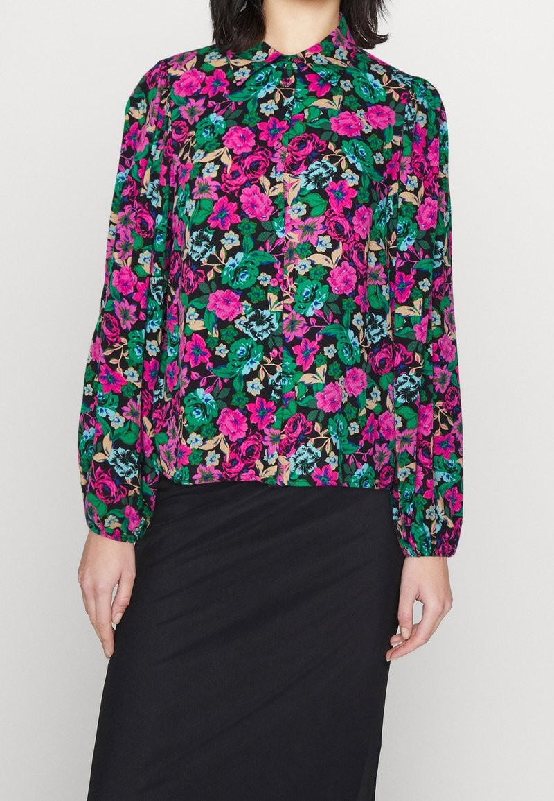 Bloemige blouse met levendige roze, groene en blauwe bloemen op een zwarte achtergrond, kraag en lange puffed mouwen.