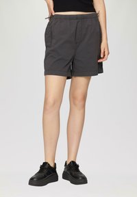 Grijze shorts met een elastische tailleband, zijzakken en een relaxte pasvorm, gecombineerd met zwarte sneakers met een dikke zool.