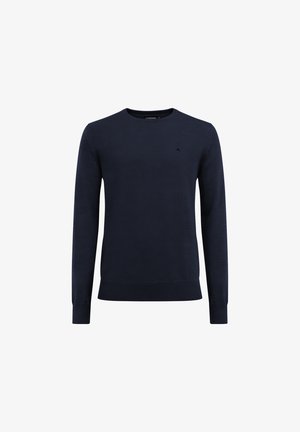 Tummansininen neulepaita, jossa on pyöreä kaula-aukko, pitkät hihat sekä ribbaus hihansuissa ja helmassa. Huomaamaton logo-ylellisyys rinnassa.