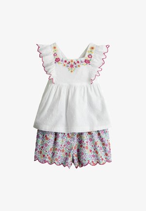 Rochie albă fără mâneci pentru bebeluși cu broderie florală roz și galbenă, margini voluminoase și pantaloni scurți asortați cu model floral și margini ondulate.