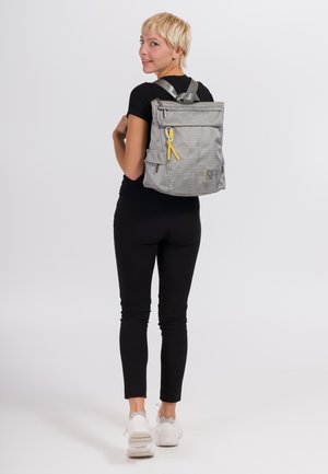 Mochila gris con material texturizado, asa superior, correas negras, bolsillo frontal con cremallera y acento amarillo en el tirador de la cremallera.