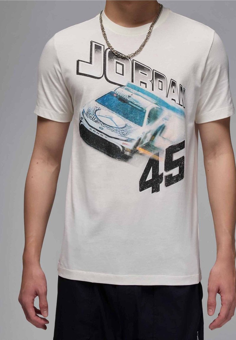 T-shirt en coton crème avec un graphique d'une voiture de course, "JORDAN" au-dessus et "45" en dessous en gras noir. Manches courtes, col rond.