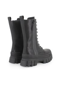 Botas negras hasta el tobillo con suela de plataforma gruesa, material de cuero, parte frontal con cordones y paneles laterales elásticos para facilitar su uso.