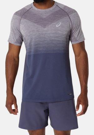 Homme portant un t-shirt de sport à manches courtes dégradé gris et bleu et un short de sport bleu uni sur fond blanc.