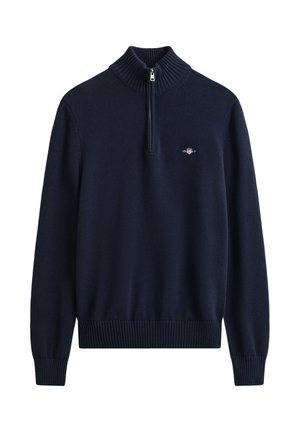 Camisola de malha azul-marinho com gola alta canelada, fecho de meio zíper e pequeno detalhe de logo no peito. Punhos e bainha canelados.