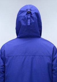 Violetinis kapisonas su lygiu paviršiumi, pasižymintis maža kilpa ant kapisono nugaros ir paprastu, elegantišku dizainu.