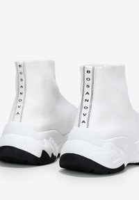 Zapatillas altas blancas con una parte superior de punto texturizado, una etiqueta en negro y blanco "BOSANOVA" audaz, y una suela de goma negra en contraste.