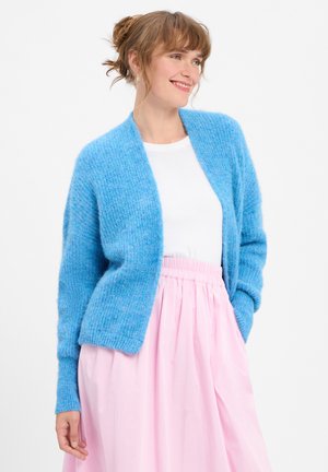 Blue knitted cardigan with a soft texture, open front, and long sleeves, paired with a light pink, pleated skirt.