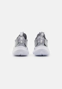Harmaa ja valkoinen Nike-lenkkeilykengät, jotka näkyvät takaa brändätyillä kantanauhoilla valkoista taustaa vasten.