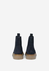 Botas de tobillo de ante azul marino con suela de goma texturizada, con tiradores en la parte trasera y un diseño clásico de Chelsea.