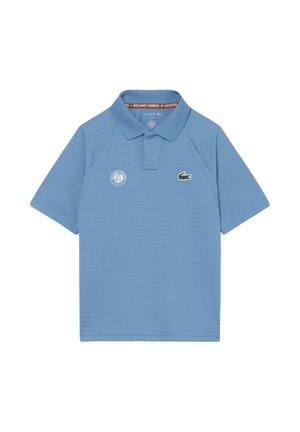 Polo Lacoste azul claro con logo de Roland Garros en el pecho izquierdo y emblema de cocodrilo en el pecho derecho, mangas cortas y cuello.