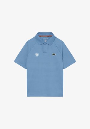 Hellblaues Lacoste Poloshirt mit Roland-Garros-Logo auf der linken Brustseite und Krokodilsymbol auf der rechten Brustseite, kurze Ärmel und Kragen.