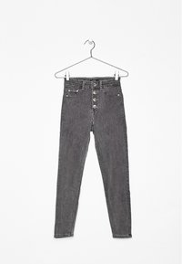 Jeans de mezclilla oscuros de talle alto con cierre de botones, bolsillos delanteros y traseros, colgados en un gancho blanco con clips metálicos.