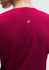 Korte mouw sportshirt in gemêleerd magenta, met een getextureerd oppervlak en een klein logo op de achterkant van de halslijn.