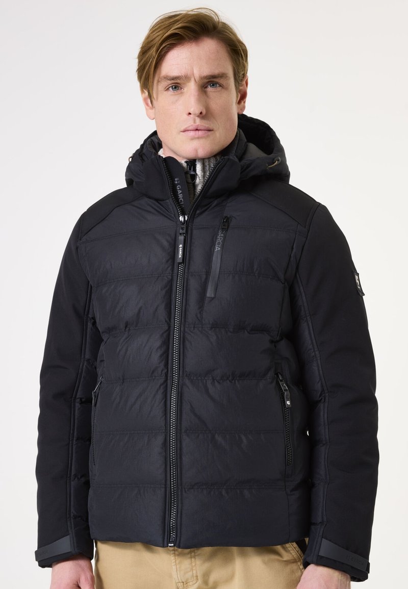 Schwarze gesteppte Jacke mit Reißverschluss vorne, Kapuze und Reißverschlusstaschen. Verfügt über eine glatte Stofftextur und ein gepolstertes Design zur Isolierung.