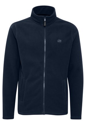 Chaqueta de forro polar azul marino con cuello alto, cremallera completa, bolsillos laterales y un logo sutil en el pecho. Textura suave y corte recto.