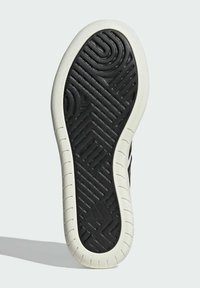 Soletta in gomma nera con un motivo geometrico testurizzato. Bordo in gomma bianca attorno alla suola. Logo del marchio visibile vicino al tallone.