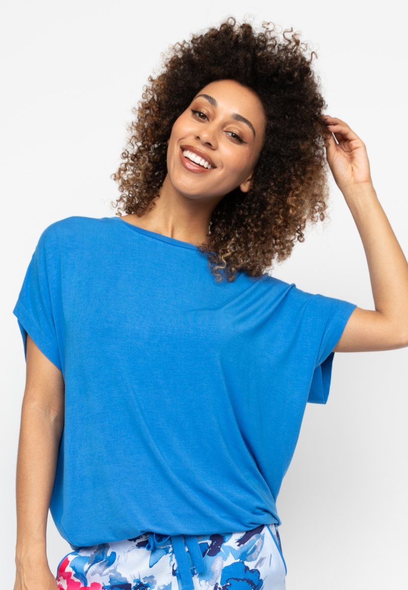 Blauwe korte mouwen top gemaakt van lichte stof, met een ontspannen pasvorm en een ronde halslijn. Gepaarde met gebloemde shorts.