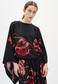 Kaftan negru cu imprimeu floral mare în nuanțe de roșu și roz, având mâneci largi și o croială lejeră. Textură netedă, design minimalist și fără închideri.