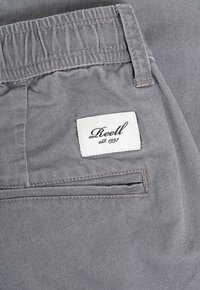 Gray pants with a textured fabric, featuring an elastic waistband, a back pocket, and a white label reading "Reell est. 1997."
