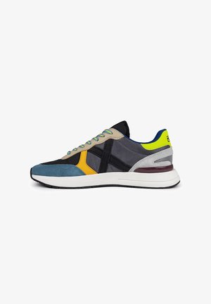 Zapatillas para hombres que presentan una combinación de tejidos en azul, gris, amarillo y negro; diseño elegante con una entresuela blanca y acentos texturizados.