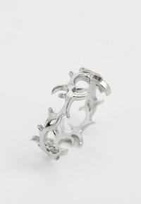 Bague en argent avec un design ajouré présentant des formes stylisées, abstraites et courbées évoquant des flammes ou des épines.