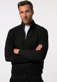 Sort zip-up sweatshirt med høj krave, ribbede manchetter og logo detail på brystet. Glat tekstur, designet til en tætsiddende pasform.