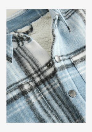 Modra karirana srajca z mehkim, volnenim občutkom z belimi in črnimi detajli. Vključuje kovinske pritiske in puhasto notranjo podlogo.