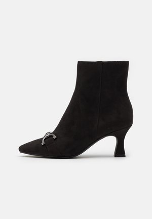 Schwarzer Wildleder-Stiefelette mit spitzer Zehe und mittelhohem Absatz, vorne mit einem metallischen Akzent für zusätzliche Details.