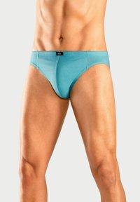 Helle blaue Boxershorts aus einem glatten Material, mit einem engen Sitz und einem schwarzen Markenaufschrift am Bund. Schlichtes Design mit minimaler Detailverarbeitung.