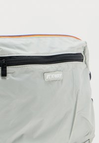 Ανοιχτό γκρι θήκη K-Way με μαύρο φερμουάρ και πολύχρωμη επένδυση στην κορυφή, που εμφανίζει το λογότυπο της μάρκας κάτω από το φερμουάρ.