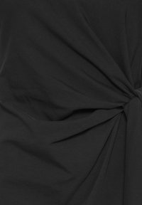 Tissu noir avec un détail de nœud créant des plis froncés et de la texture.
