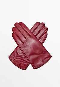 Guanti in pelle bordeaux con una superficie liscia, forma allungata e design a cinque dita, posati piatti in posizione incrociata.