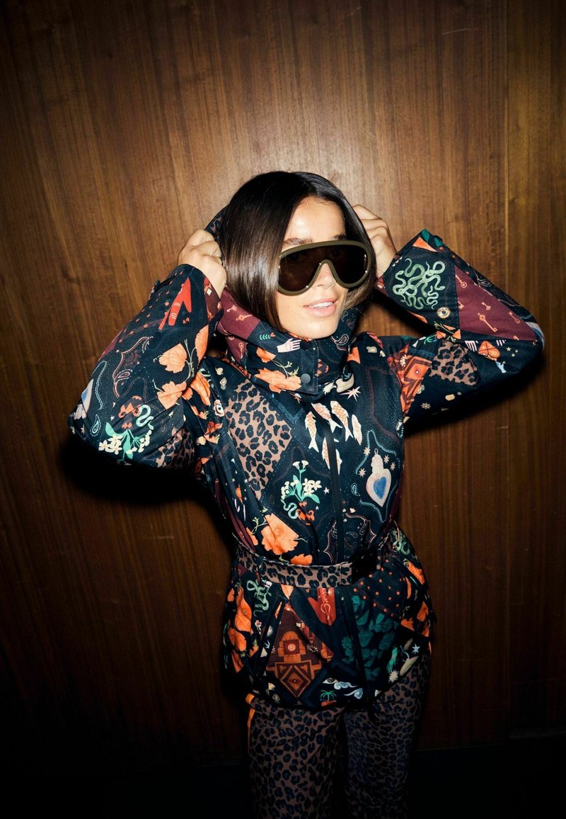 Chaqueta de invierno estampada con vibrantes diseños florales y de animales, combinada con pantalones a juego. Cuenta con capucha, cintura con cinturón y gafas de sol extragrandes.