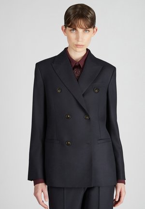 Dubbelzijdig marineblauw blazer gemaakt van gestructureerde stof met messing knopen, notch revers en twee voorkeurszakken, gecombineerd met een bordeauxrood hemd.