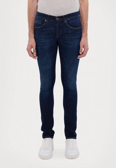 Jeans skinny in denim blu scuro, con tasche frontali, zip e leggero sbiadimento. Abbinati a sneaker bianche.