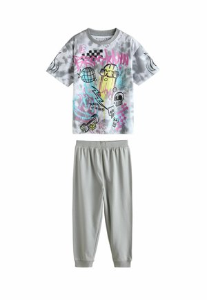 Graafi T-paita harmaassa sitruunankynsipainannassa, jossa on värikkäitä printtejä ja kuvioita, yhdistettynä kevyisiin, yksivärisiin vaaleanharmaisiin joustovyötäröhousuihin.