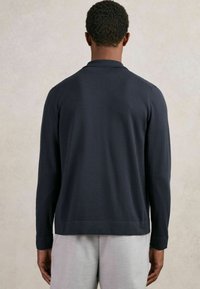 Polo de manga larga azul marino con cuello, puños acanalados y dobladillo recto. Confeccionado con un material suave, diseñado para un ajuste relajado.