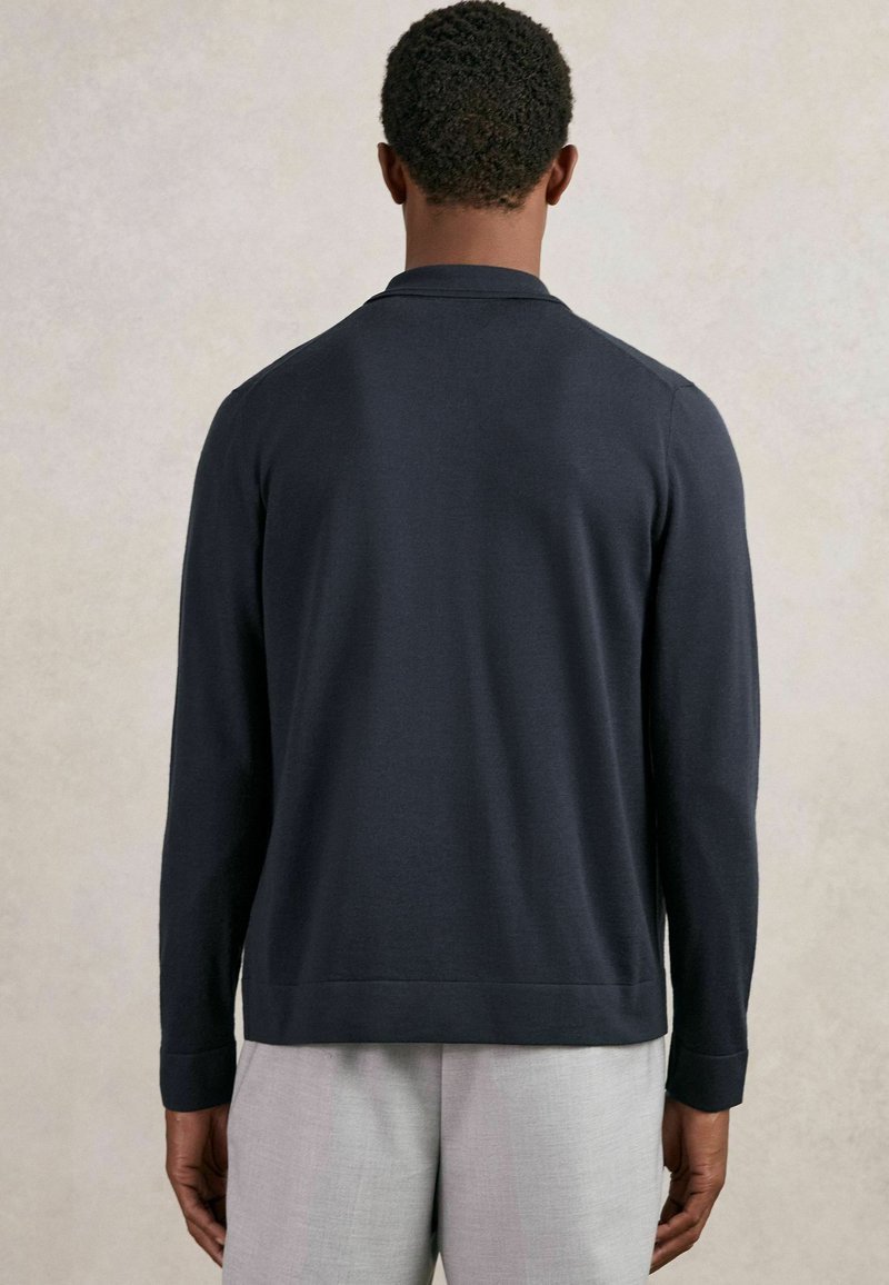 Polo de manga larga azul marino con cuello, puños acanalados y dobladillo recto. Confeccionado con un material suave, diseñado para un ajuste relajado.