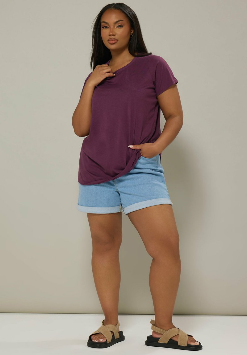 Lilla kortærmet t-shirt med en sidelomme, parret med lyseblå denimshorts med opkrøllede kanter og brune snøre sandaler.