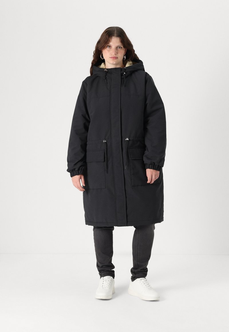 Parka noire avec une capuche, fermeture éclair sur le devant et deux grandes poches avant. Fabriquée dans un matériau durable, elle dispose de poignets élastiques et d'une coupe décontractée.