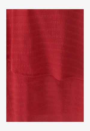 Tessuto rosso texturizzato con un aspetto morbido e stratificato, caratterizzato da lievi variazioni di tono e una superficie leggermente stropicciata.