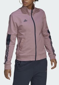 Roze jack met ritssluiting en donkerblauwe accenten, voorzien van een hoge kraag, geribbelde manchetten en zijzakken. Adidas-logo op de borst.